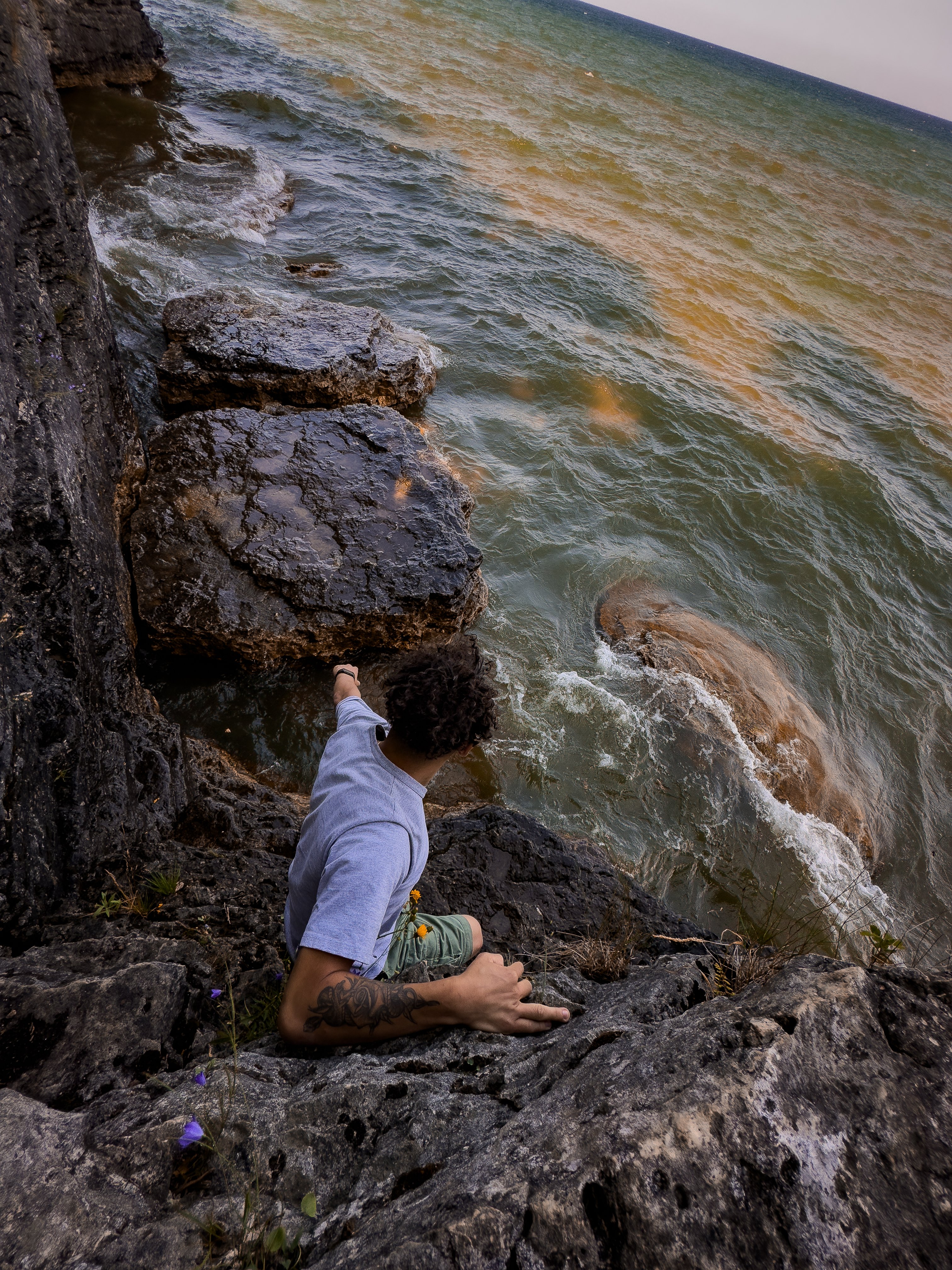 Person on cliff edge above water, facing away